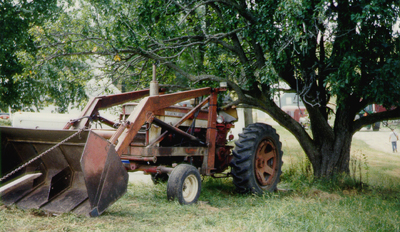 photo of tractor with front-end loader backed into tree