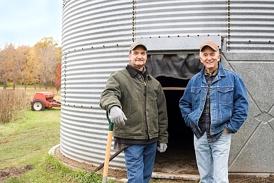 Two farmers standing in front of grain bin