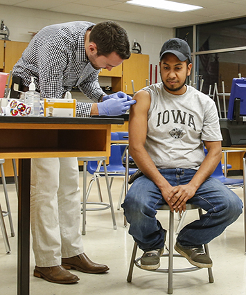 University of Iowa third year medical student Brian Guetschow gives a flu shot to Jose Santos of West Liberty 