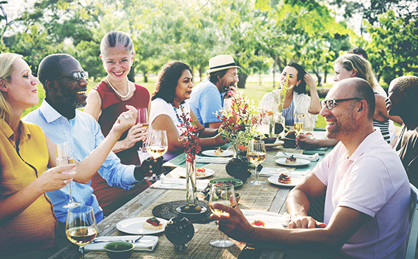 group of diverse adults dining at long table outdoors