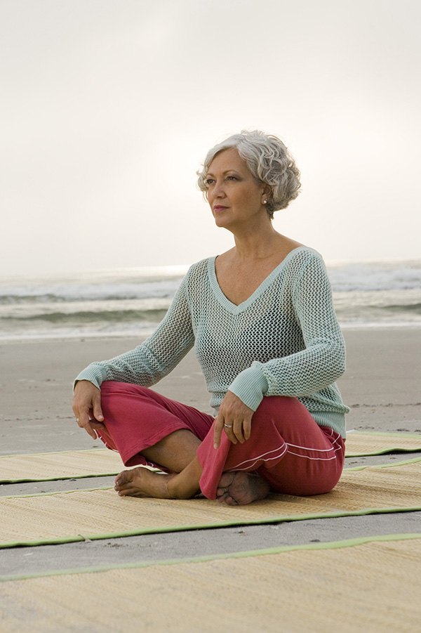 Mature woman exercising on a mat at the beach