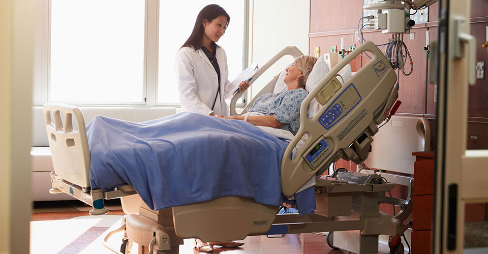 Caregiver standing at hospital bedside of a patient