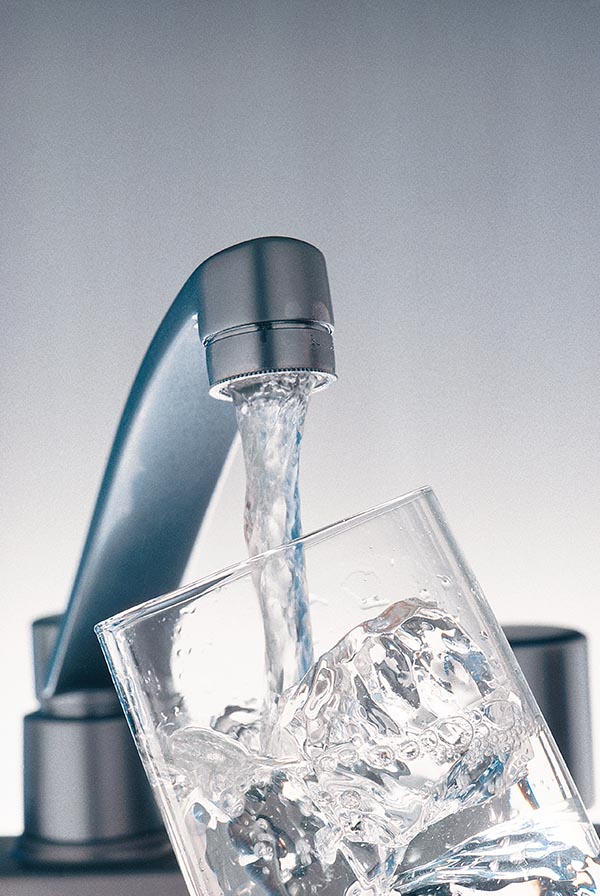 Faucet filling glass of ice with water