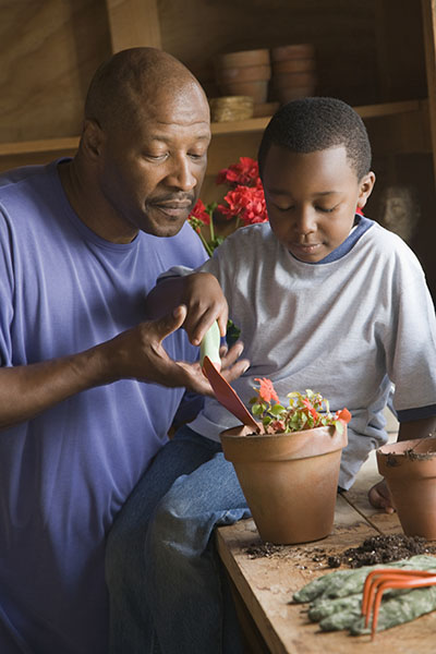 Boy gardening with the help of his grandfather