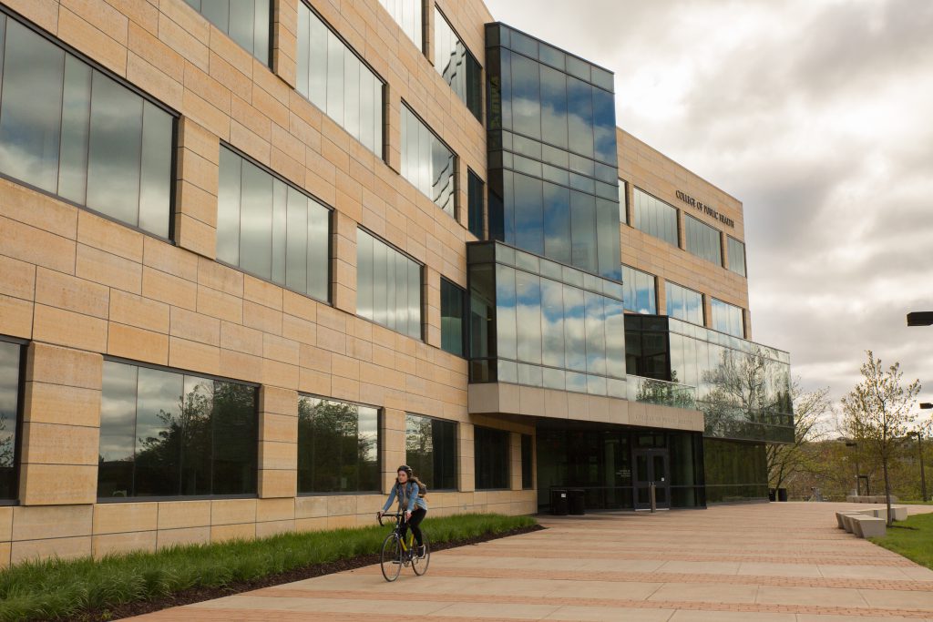 A cyclist rides on the south patio of the College of Public Health Building.