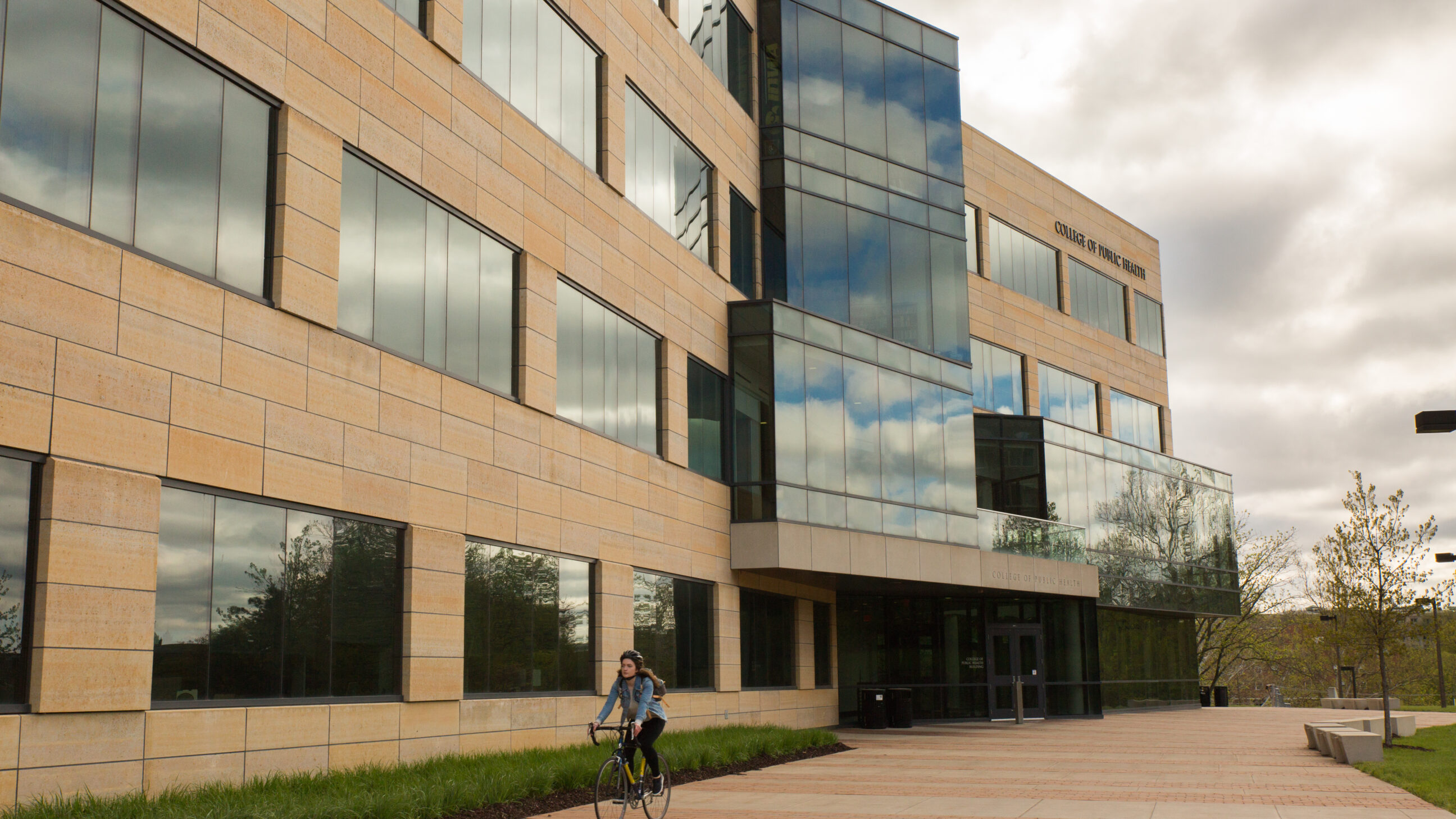 A cyclist rides on the south patio of the College of Public Health Building.