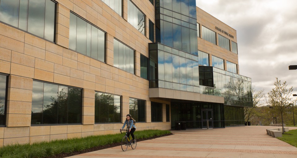 A cyclist rides on the south patio of the College of Public Health Building.