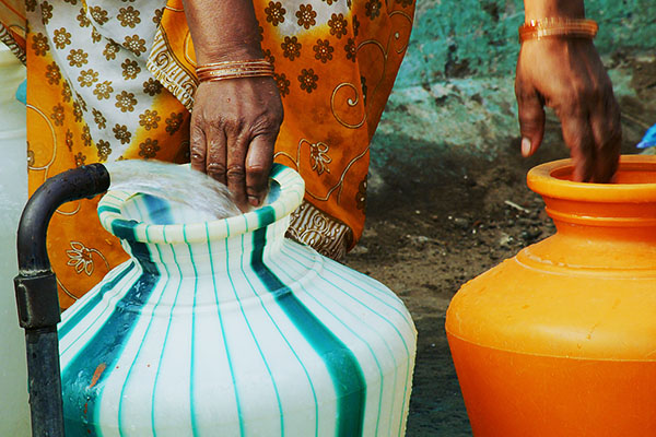 photo of a woman collecting water in plastic pots