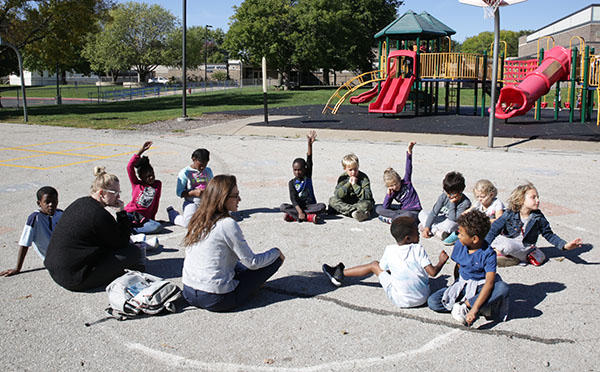 a group of elementary kids sit in a circle on the playground