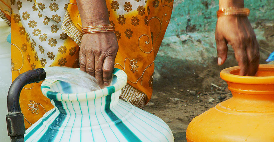 Image of a woman with wash basins of water in India.