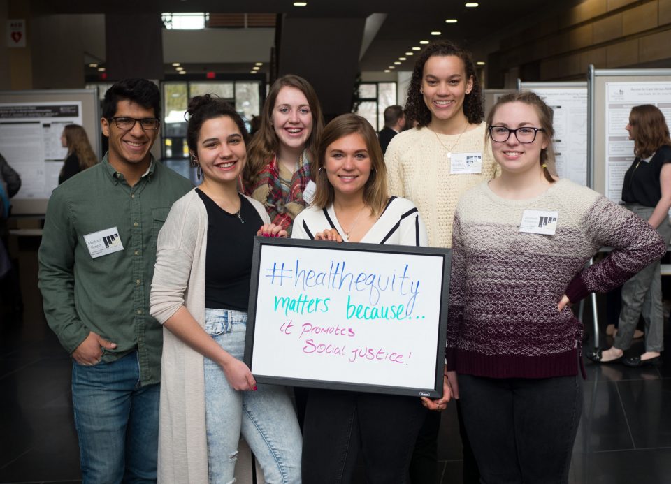 Students hold up sign saying "#healthequitymatters because it promotes social justice."