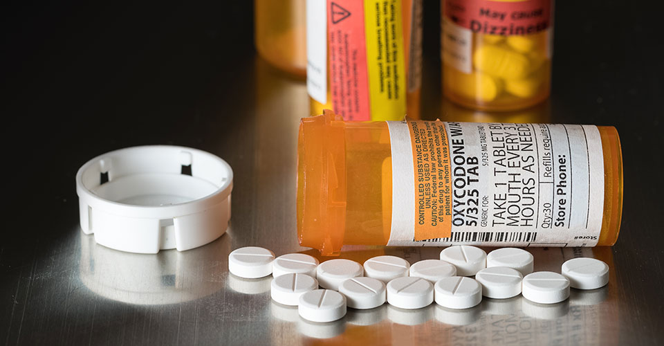 Image of opioid pills in medicine bottles on a table.