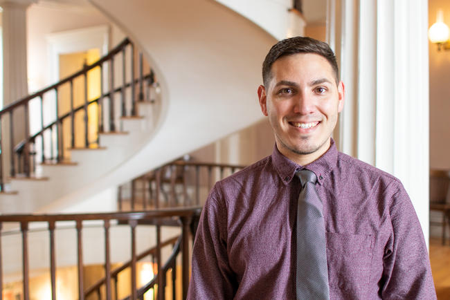 Student standing in front of spiral staircase