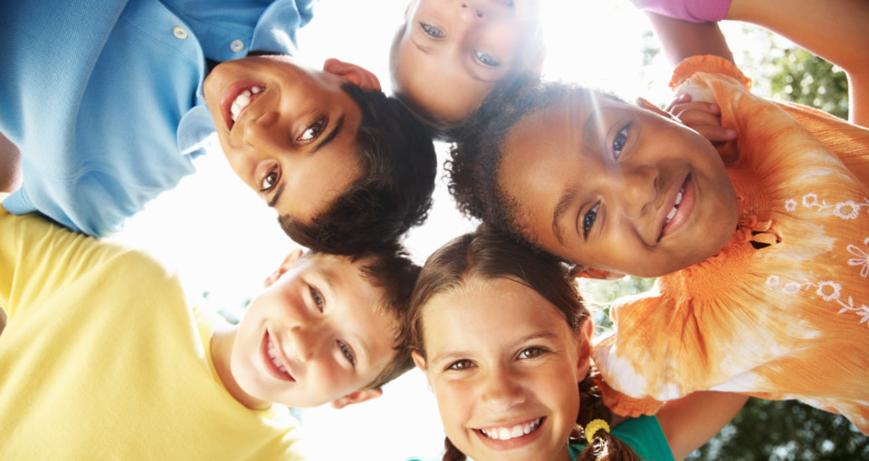 Upward view of a multiracial young friends making a huddle against sky