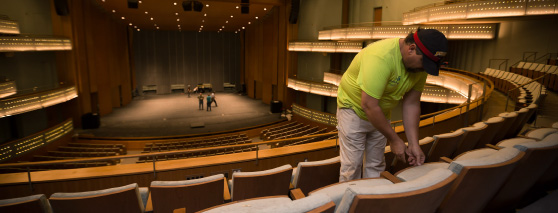 a worker tends to a seat in Hancher Auditorium