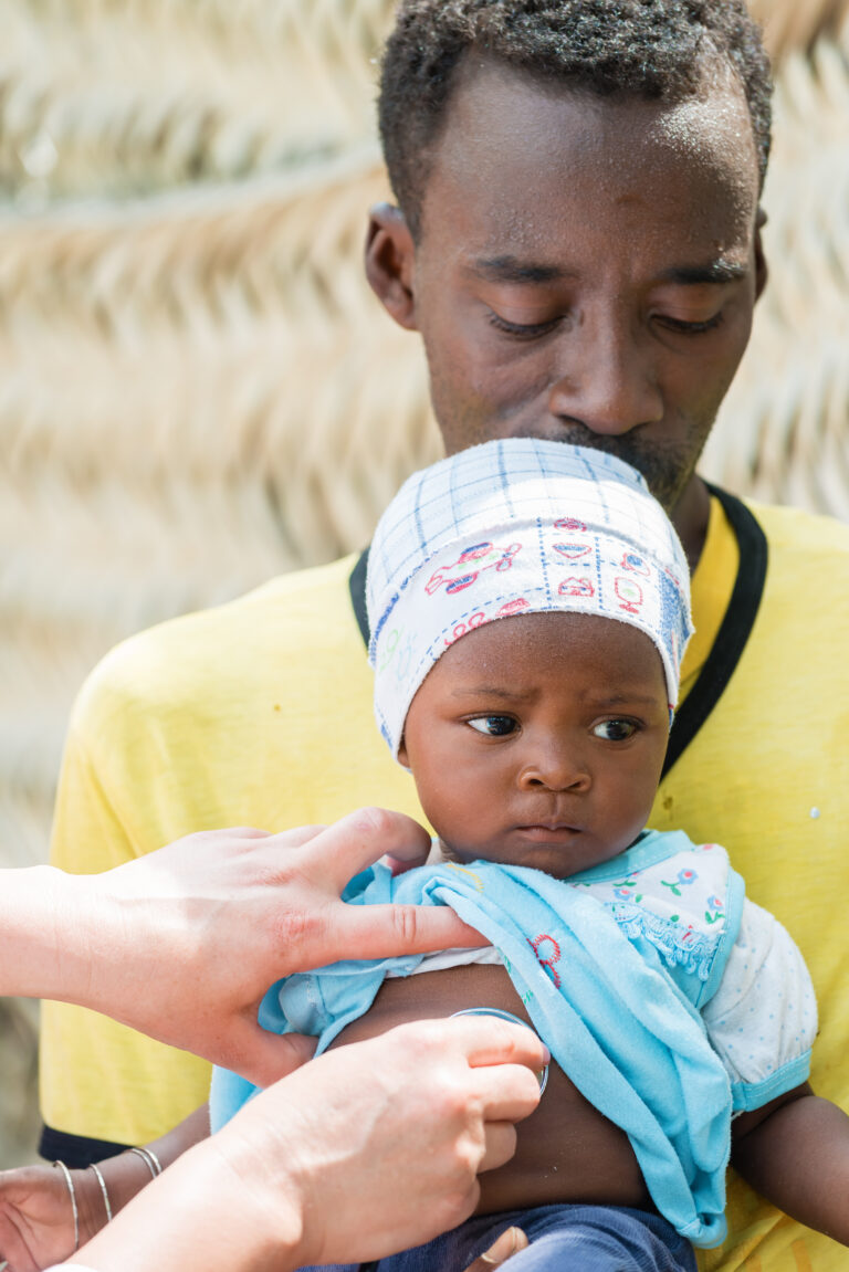 doctor listening to heart beat of baby with stethoscope. Father holding the baby