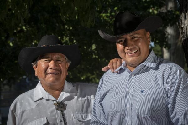 Two men  wearing cowboy hats smiling 