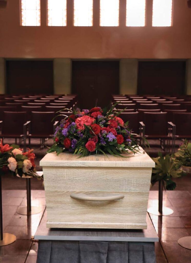 a casket topped with flowers in an empty funeral home