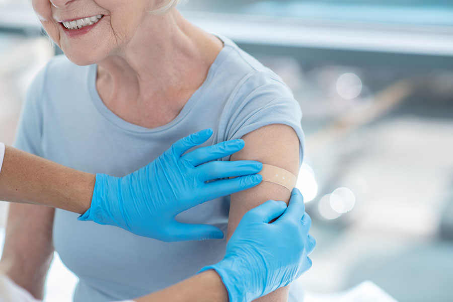 an older woman receives a bandage on her arm after a vaccine