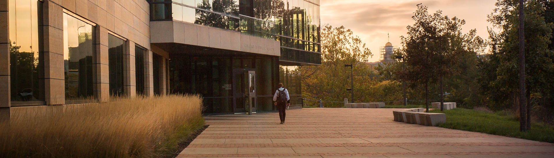 Student walking into the College of Public Health Building at dawn.