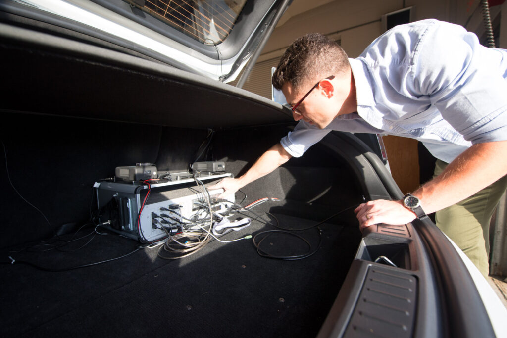 A public health researcher makes an adjustment to instrumentation in a vehicle.