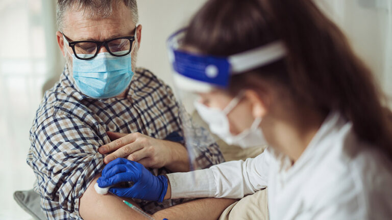 nurse giving older man a COVID vaccine