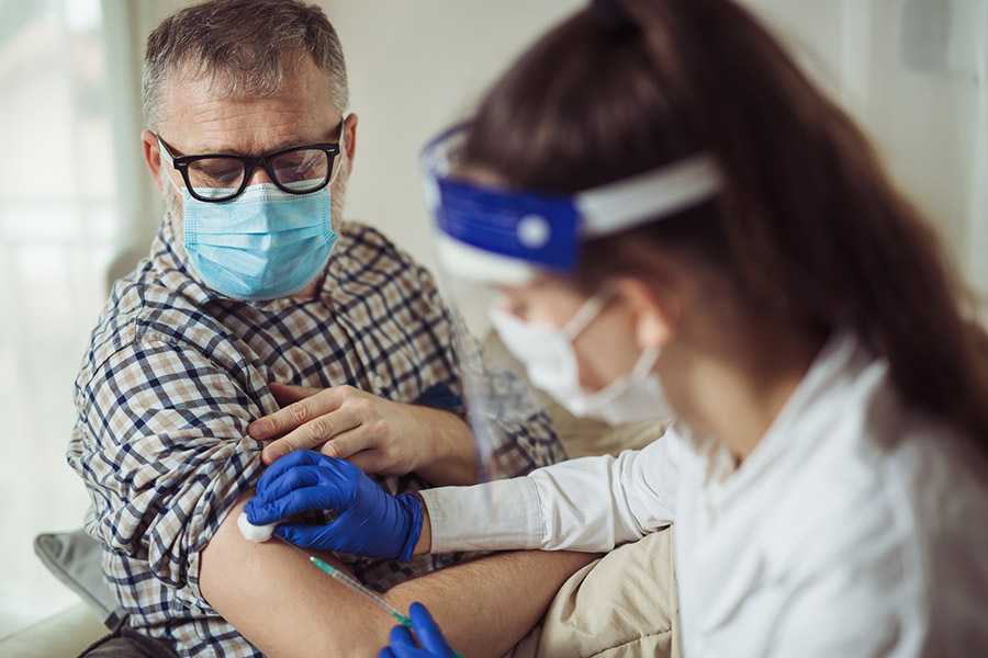 An older man gets a vaccination in a clinic.