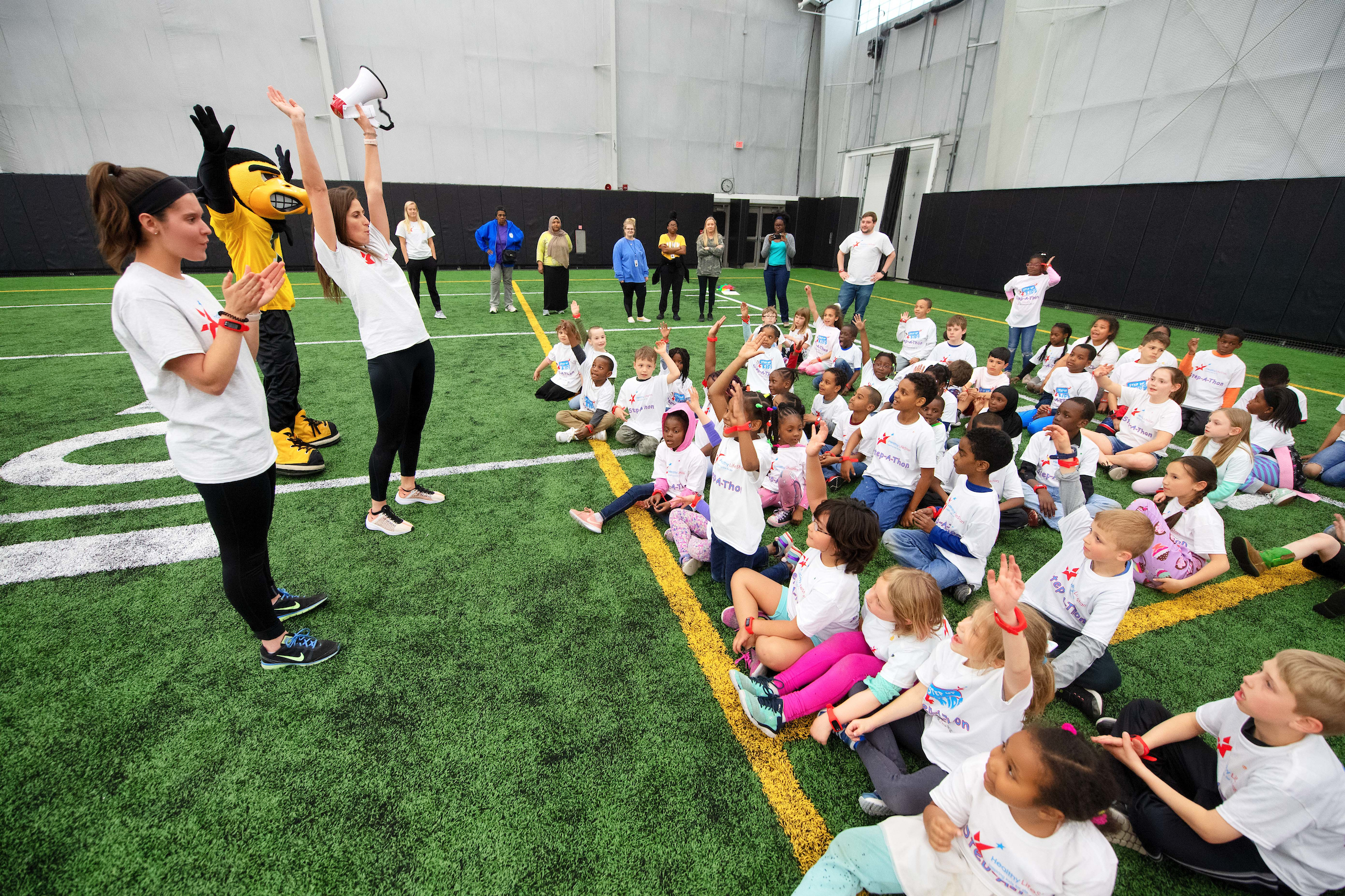 Team leaders and Herky the Hawk lead children in an activity at a Healthy Lifestars event.