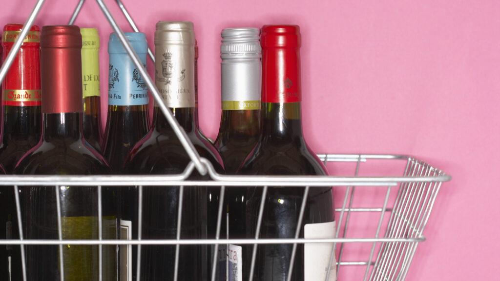 A shopping basket filled with unopened wine bottles