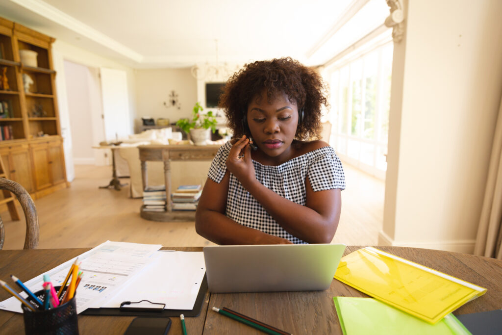 A woman working from home on a laptop and phone