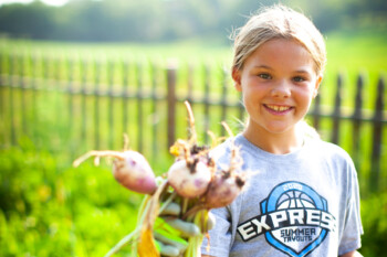 girl in garden holding freshly picked vegetables