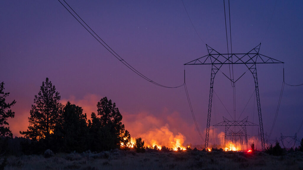 a California wildfire burns under a high voltage electrical transmission line