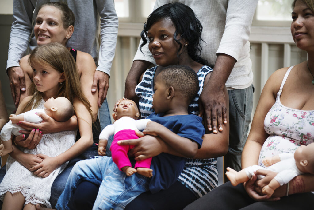 a diverse group of pregnant women attend a class with their partners and children