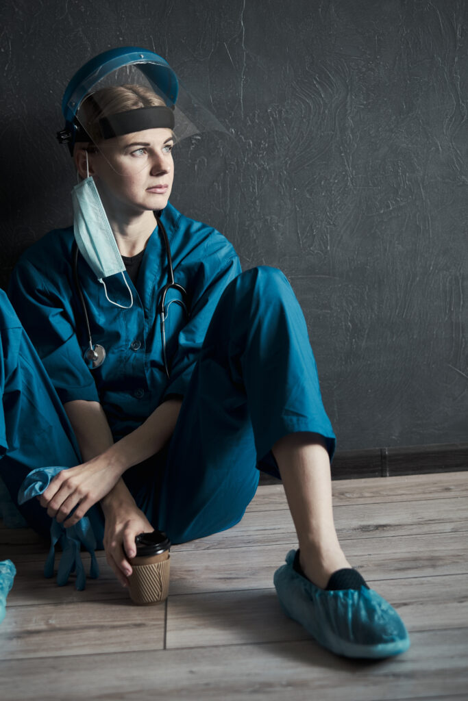 tired medical worker taking a coffee break, sitting on the floor