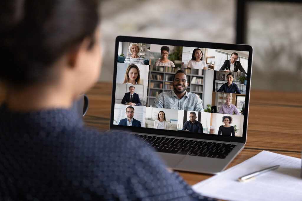 over shoulder view of a laptop screen showing multiple people taking part in an online meeting