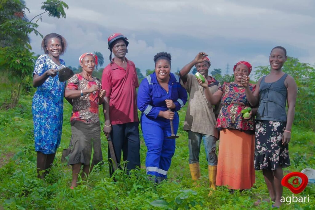 Gift Udoh (center) stands in a green field with a group of farmers.