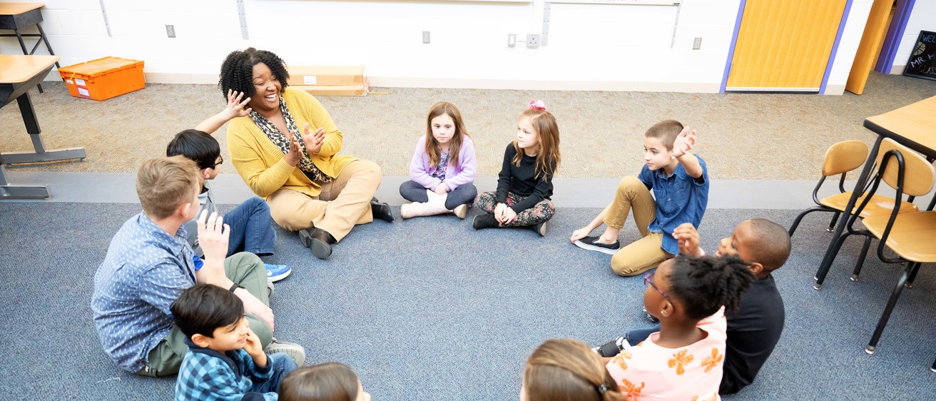 an elementary teacher sitting in a classroom with students