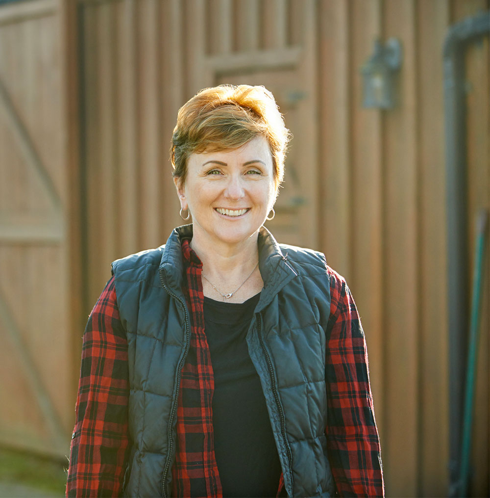 a female farmer standing outside a barn