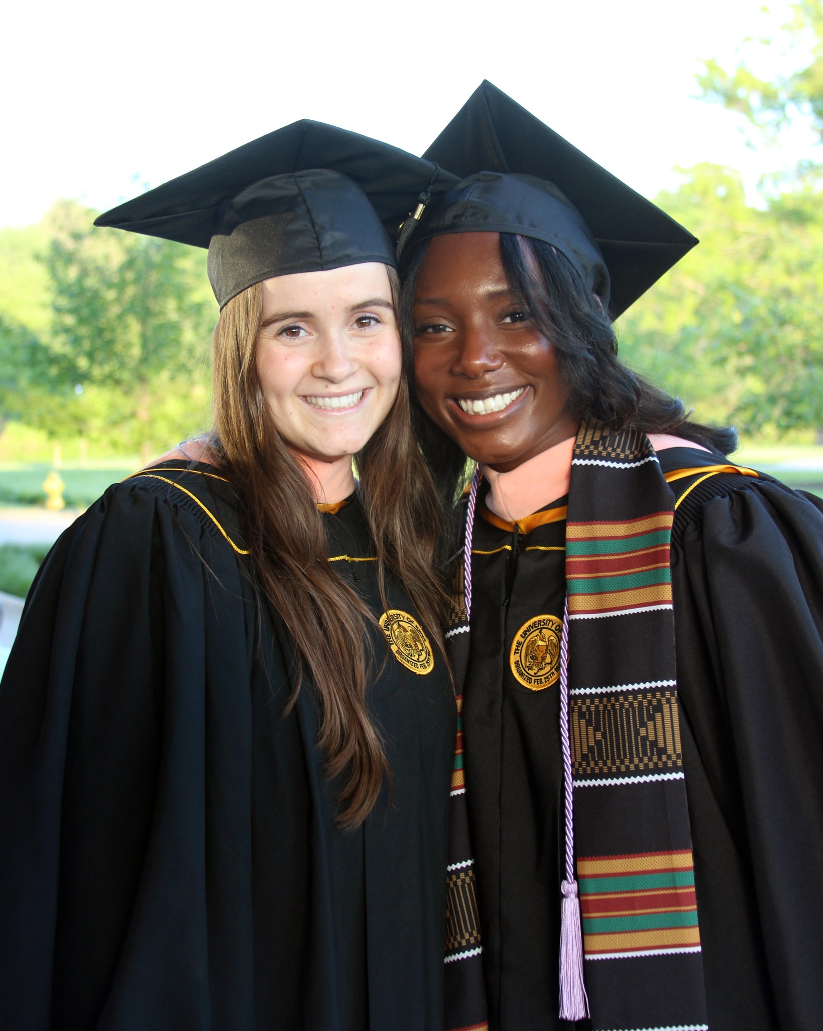 Two public health students smile for the camera at the 2024 commencement ceremony.