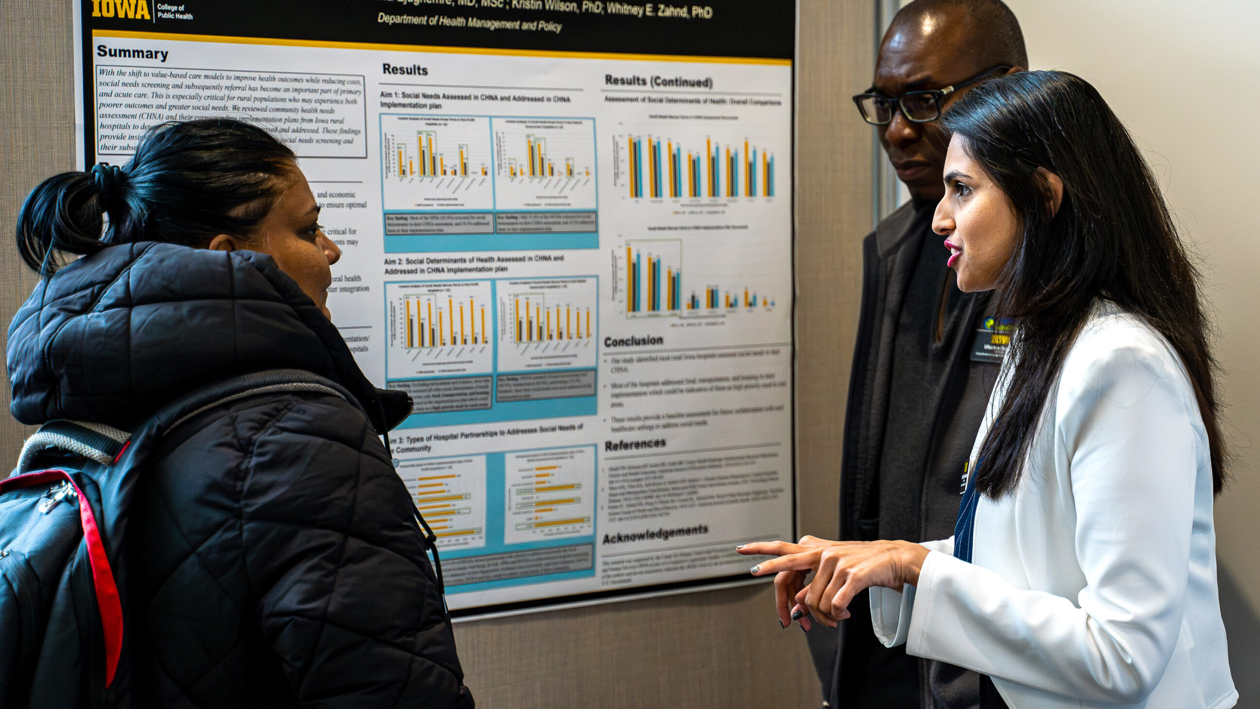 College of Public Health students discuss research at a poster session in the atrium of the College of Public Health Building.
