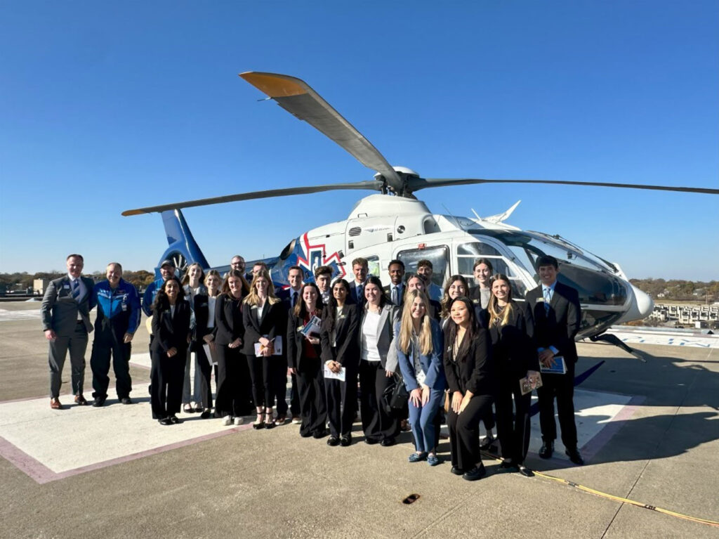 Students standing in front of a helicopter.