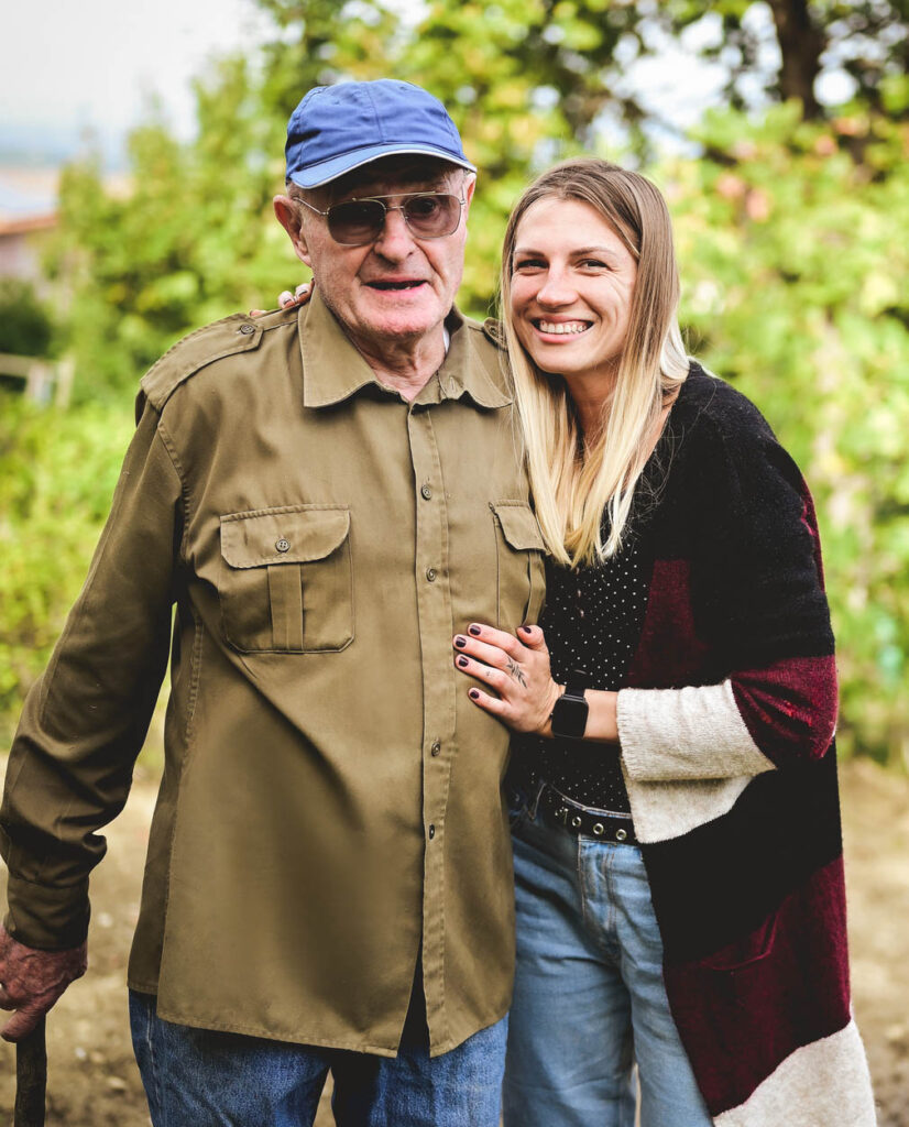 A senior man with his granddaughter in a garden.