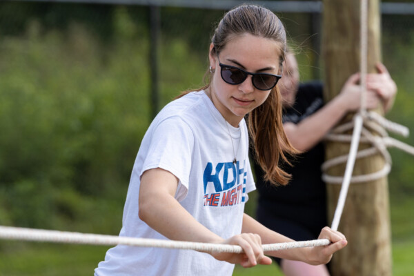 An MHA student works her way across a rope as part of the MHA ropes course challenge in 2025.