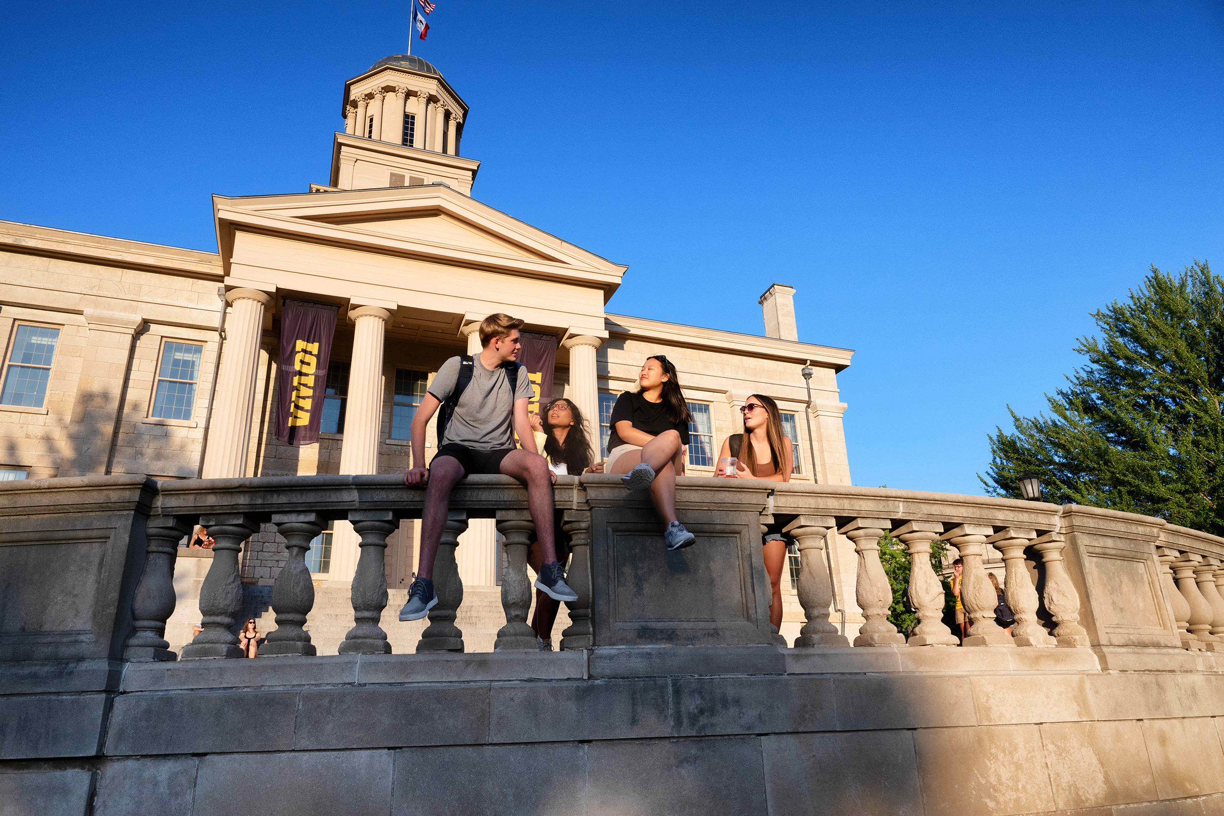 Students sit on the railing outside of the Old Capitol.